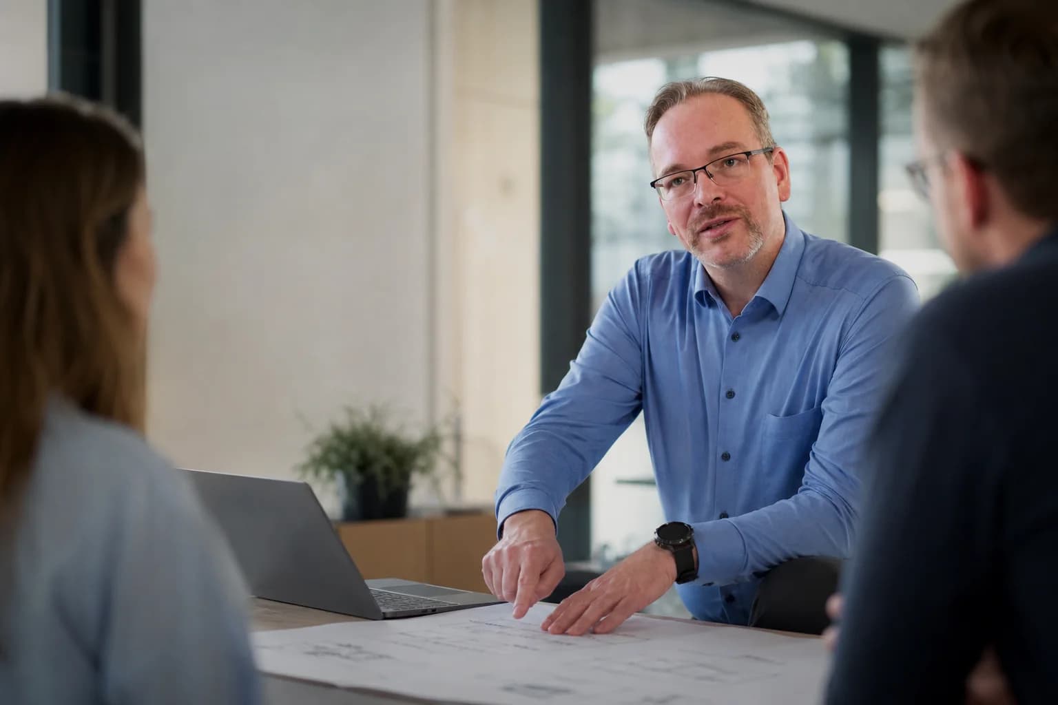Christian Höhle bespricht mit zwei Mitarbeitenden einen konkreten Arbeitsprozess